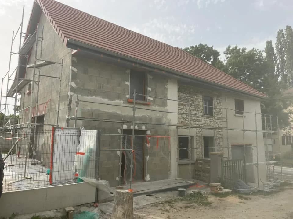 Façade de maison ancienne en parpaings et pierres pendant le ravalement, échafaudage complet